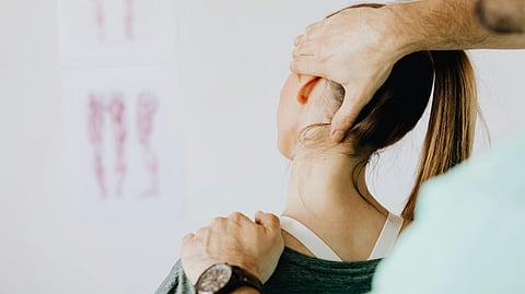 A chiropractor helping a patient to extend the neck during therapy.