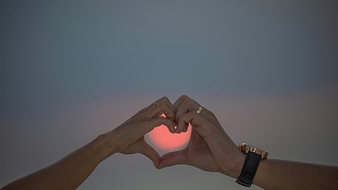 Two people forming a heart shape with their hands, symbolizing love and connection amidst discussions on heart health