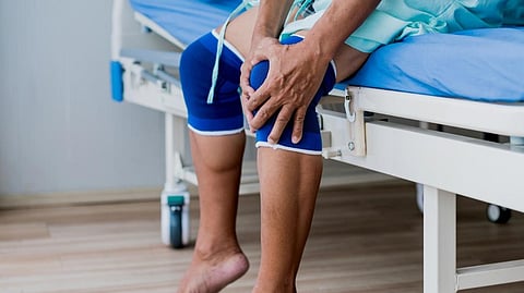 The image shows a man holding his knee.