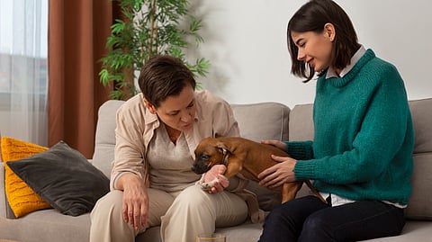 two ladies playing with dog while sitting on the sofa