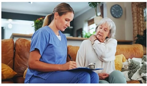 A nurse is writing some notes in a pad after talking to a senior lady.