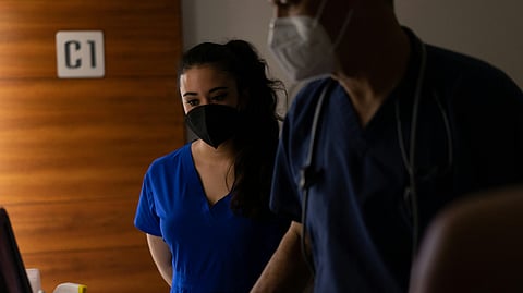 Two nurses in a dark background.