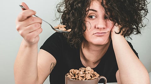 A woman is looking at the chocos she spooned out from a bowl full of it.