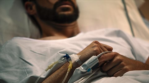 Close-up of a patient lying in a hospital bed with an IV line in his hand, receiving intravenous treatment.