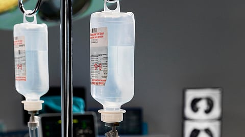 A hospital room featuring IV bags hanging and a medical monitor displaying patient information.