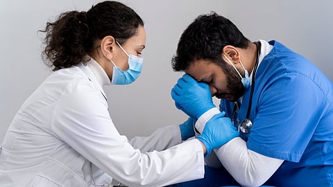 A female doctor is seen consoling a distressed male doctor in the hospital.