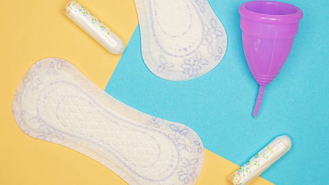 Sanitary pads and menstrual cup on a bright yellow-blue background, highlighting menstrual health.
