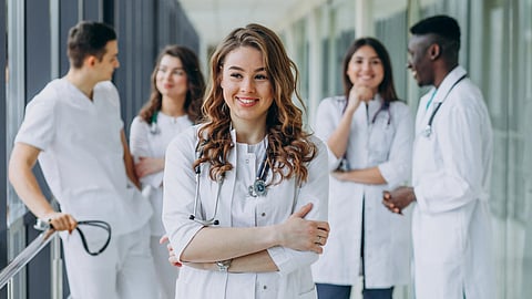A group of doctors in white coats standing together in a hospital hallway, engaged in conversation.