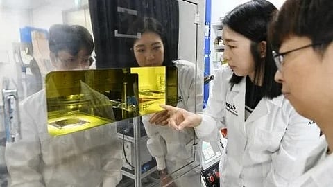 Two individuals in lab coats examining items inside a glass display case in a laboratory setting.