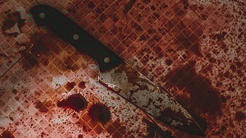 A bloodied knife lies on a hospital floor surrounded by a pool of blood.