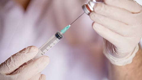A healthcare worker draws Amikacin injection into a syringe from a medication vial at a hospital.
