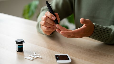 A person wearing green shirt checking glucose level using a glucometer.