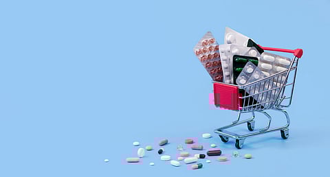 Shopping cart with pill blister and medicines in glass on white background.