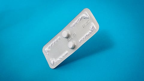 A strip of pills placed on a blue background.