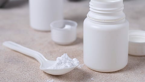 A white powder in a plastic spoon kept near a white bottle.