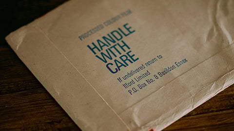 A white envelope labeled "Handle with Care," emphasizing the importance of careful handling.