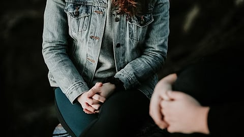 A close-up of a woman sitting wearing a grey denim jacket.