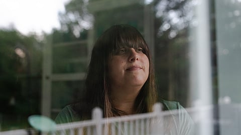A woman named Erica Kahn looking outside through her window.