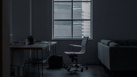 A dimly lit room featuring a couch and a desk, creating a cozy yet professional atmosphere.