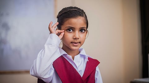 Image of a deaf girl wearing white kurta and red dupatta.