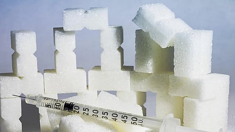 Image showing sugar blocks and an insulin syringe in front of it.