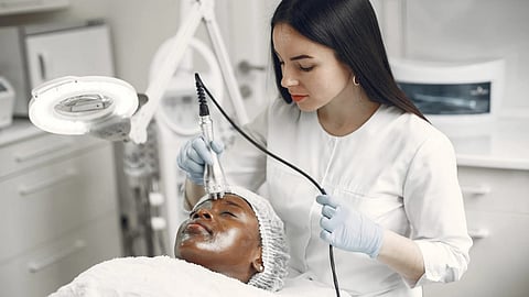 Young dermatologist giving beauty treatment to a woman in a clinical setting.