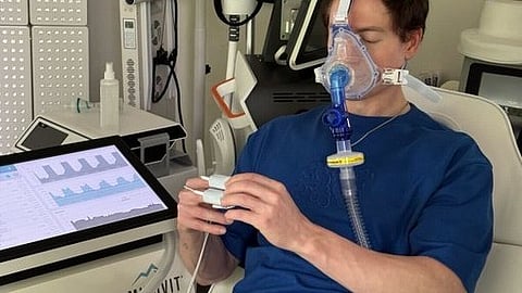 Bryan Johnson wearing an oxygen mask during his biohacking therapy session in a hospital setting.