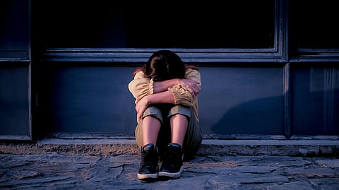 A woman sitting on ground facing downwards.