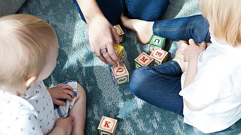 Image of children playing with their parents on a bed.