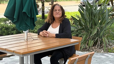 Francoise Cham sitting on a bench with her arms crossed.