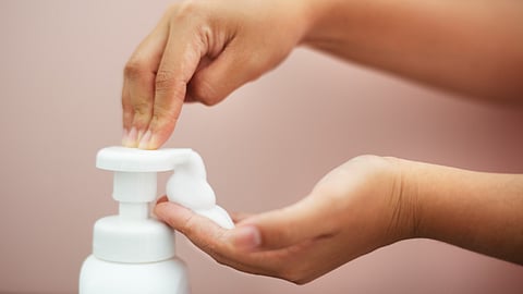 Image shows hand pressing pump bottle to dispense handwashing soap liquid.