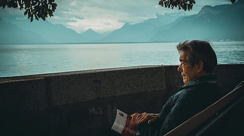 Image of an old man in blue shirt seeing the sea view.