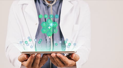 A doctor in a white coat holds a tablet with holographic medical icons (heart, DNA, stethoscope), symbolizing digital healthcare innovation in a clinical setting.