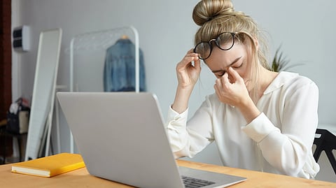 A woman rubbing her eyes off after prolonged sitting in front on laptop. 