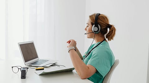 A female doctor sitting and having a video call on laptop.