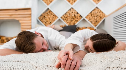 A couple lying down a bed on their front. 
