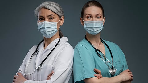 Image of a hardworking doctor and a nurse that can improve your appearance with medical procedures posing in front of a blue background.