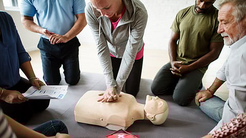 A group of people practicing CPR on a dummy. 