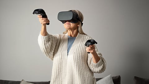 Image shows woman using a virtual reality headset and controllers.