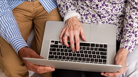 A top-down shot of a senior couple using a laptop.