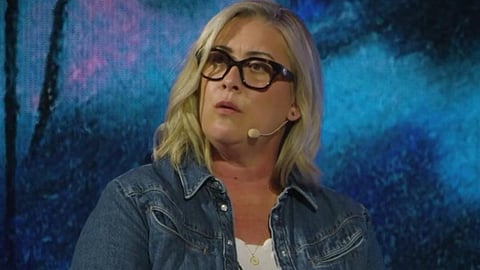 Image of Caroline Darian wearing spectacles and a blue jacket with white t-shirt, having blue background.