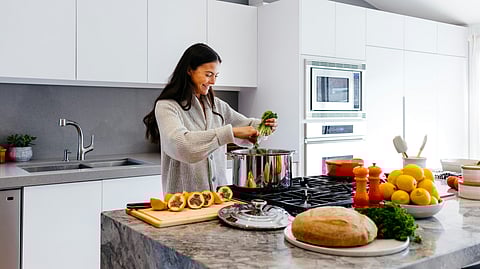 Woman making a nutritious breakfast using various fruits and vegetables in her kitchen counter for a healthy lifestyle.