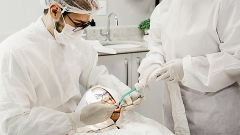 Image of an orthodontist performing a gum grafting procedure in a clinical setting.