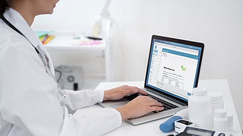 A lady doctor typing some details into a PC.