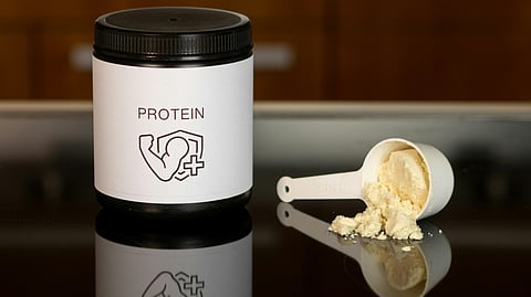 Image of a protein powder box and a scoop having protein powder.