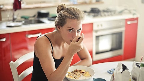 Woman eating breakfast on dining table in her house.