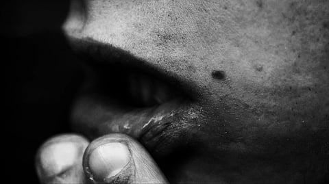 A close-up of a person's face with their hand on their mouth, indicating a dry mouth expression.
