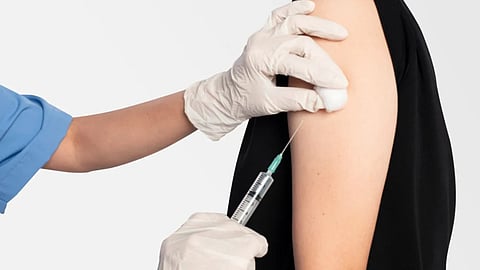 An image showing a person getting a vaccine shot from a healthcare worker in blue scrubs.