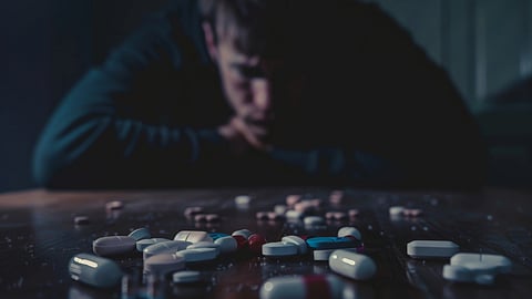 A young man looking at some spilled drugs on a table.