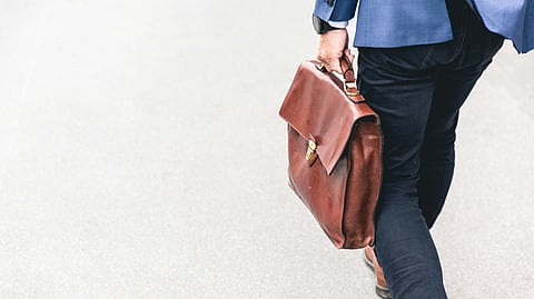 Image of a man walking with his office bag.